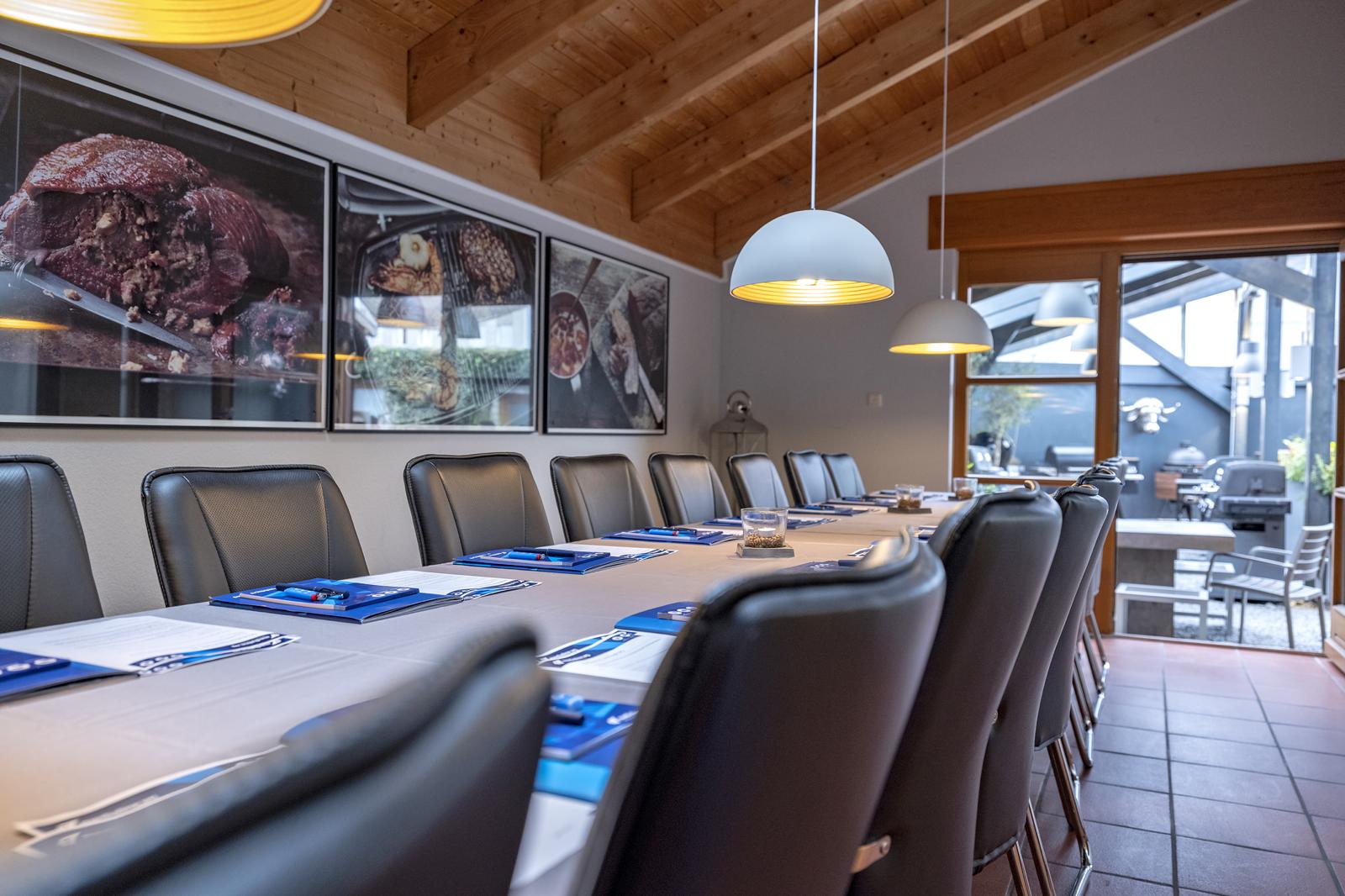 Tagungsraum im BBQ Raum Hürth mit großer Tafel für 18 Personen, eingedeckt mit Notizblöcken – ideale Umgebung für Workshops, Seminare und Teamevents